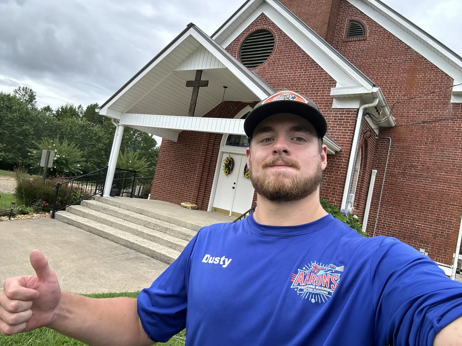Aaron, owner of Aaron's Pressure Washing, giving thumbs up with professional equipment