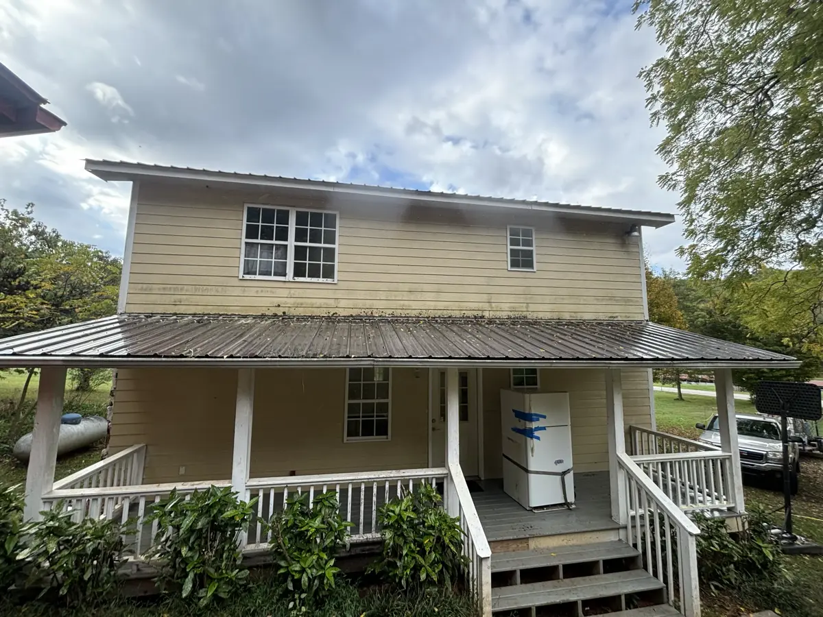 Yellow house exterior with dirt buildup before washing